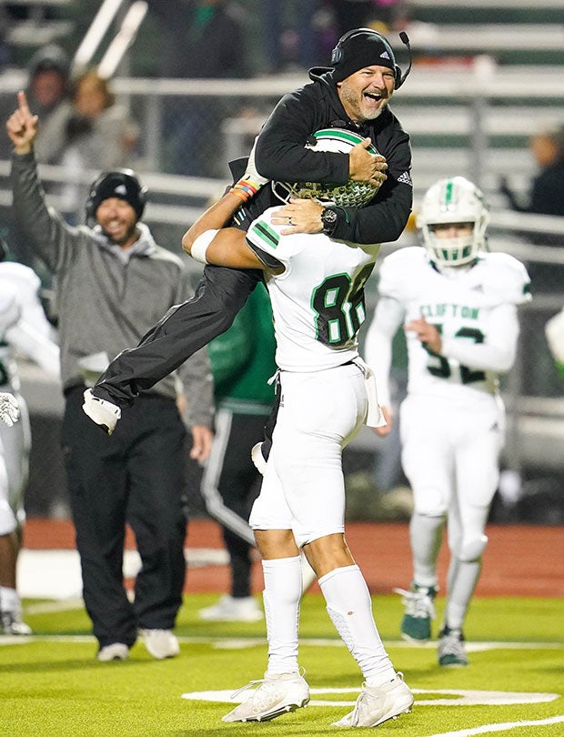 Clifton (Texas) head coach Chuck Caniford jumps into the arms of TJ Ferch while celebrating during their UIL 3A Division 2 Region II Bi-District playoff game.