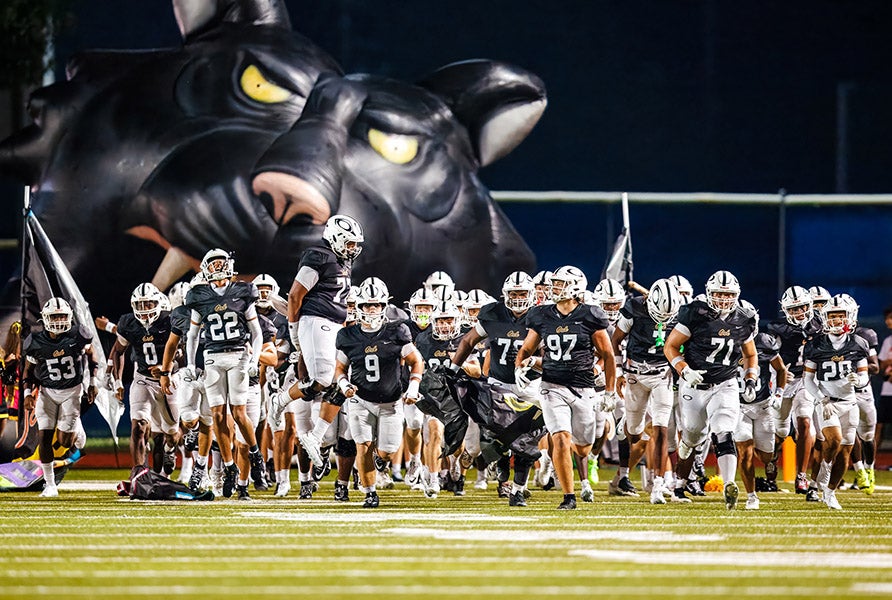 Emerging from a giant black cat, the Klein Oak Panthers of Texas have been one of the unluckiest teams in the nation this season with a record of 3-4 despite outscoring opponents by more than 100 points. (PHOTO: Rick Berns)