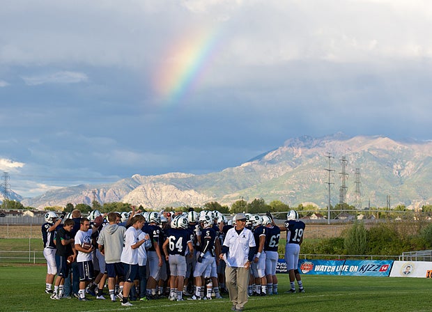 Syracuse (Utah) players gather as a rainbow appears in the distance.