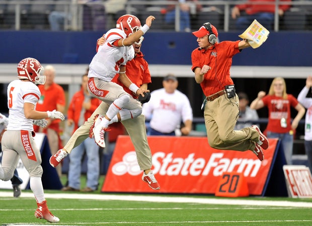 Bremond (Texas) head coach Jeff Kasowski (right) goes airborne while celebrating with players and a coach in the closing moments of the Tigers' 28-21 win over Albany in the UIL 2A Division 2 state title game at AT&T Stadium in December.