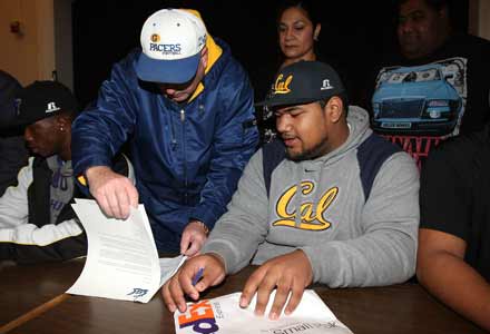 Grant coach Mike Alberghini helps Viliami Moala review his letter of intent paperwork to attend the University of California during a signing ceremony Wednesday morning at the school.