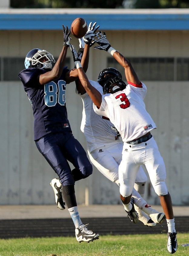 A Compton (Calif.) receiver fights with two Dominguez (Compton, Calif.) defenders for a jump ball.