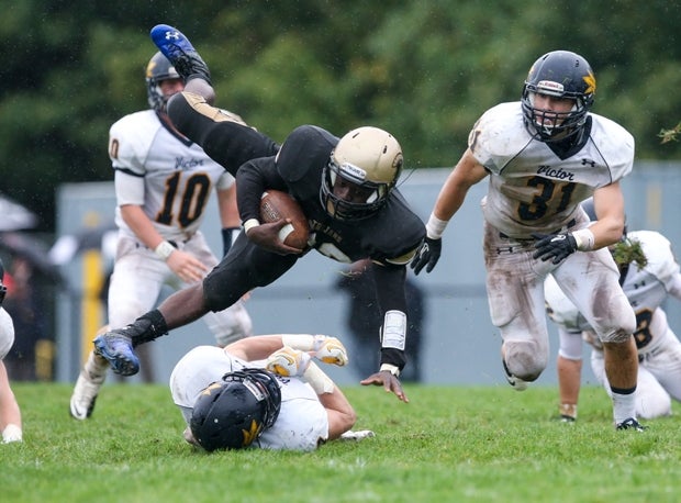 A ballcarrier for Greece Athena (Rochester, N.Y.) takes a tumble as Victor (N.Y.) defenders give chase.
