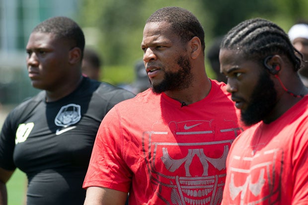 Miami Dolphins defensive lineman Ndamukong Suh (middle) is sandwiched between 5-star recruit Derrick Brown (left) and a Opening coach.