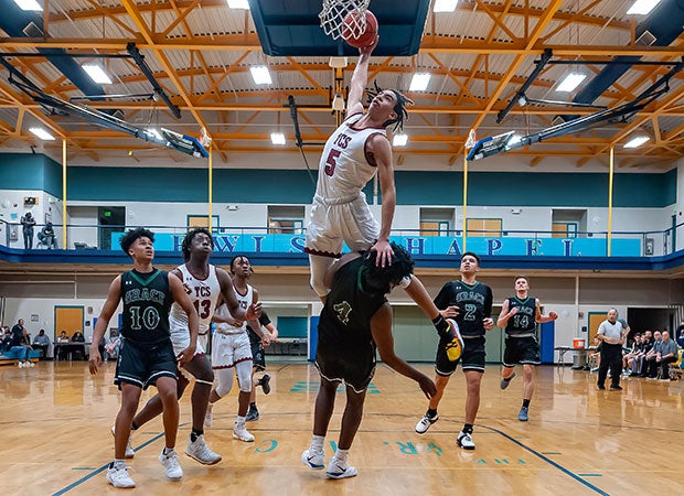 Guard Freddie Dilione of Trinity Christian (N.C.) leaps for a dunk attempt over a Grace Christian defender during a NCISAA 1A state playoff game.