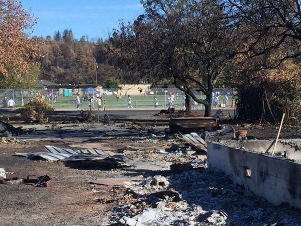 A destroyed property across the street from Middletown High School while a girls soccer game takes place in the background.  