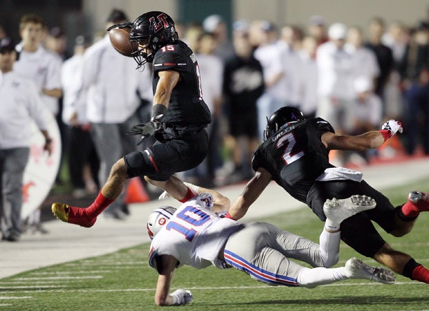 Lake Travis receiver Maleek Barkley hurdles over a Westlake defender