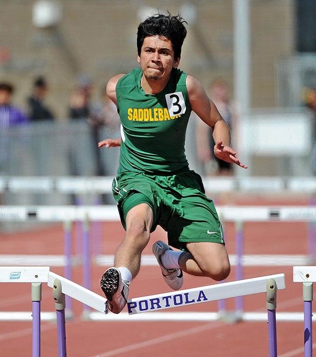 A Saddleback (Calif.) track athlete bursts through a hurdle while competing in the Earl Engman Relays in Southern California.