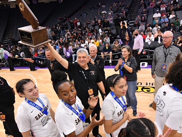 Salesian coach Stephen Pezzola holds up the school's first state title in a girls sport. 