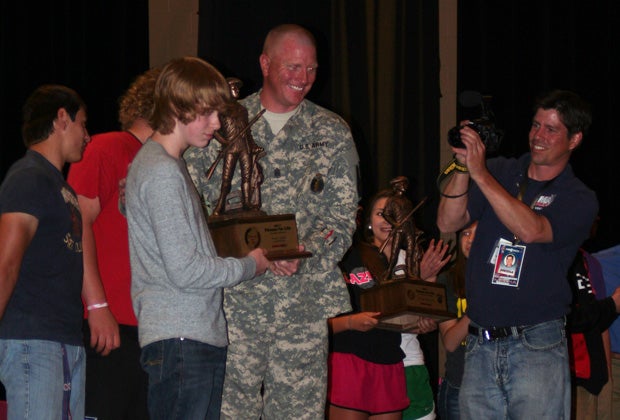Sergeant Major Shawn Fisher presents Aedan Liggett with his trophy for earning the title of most improved student.