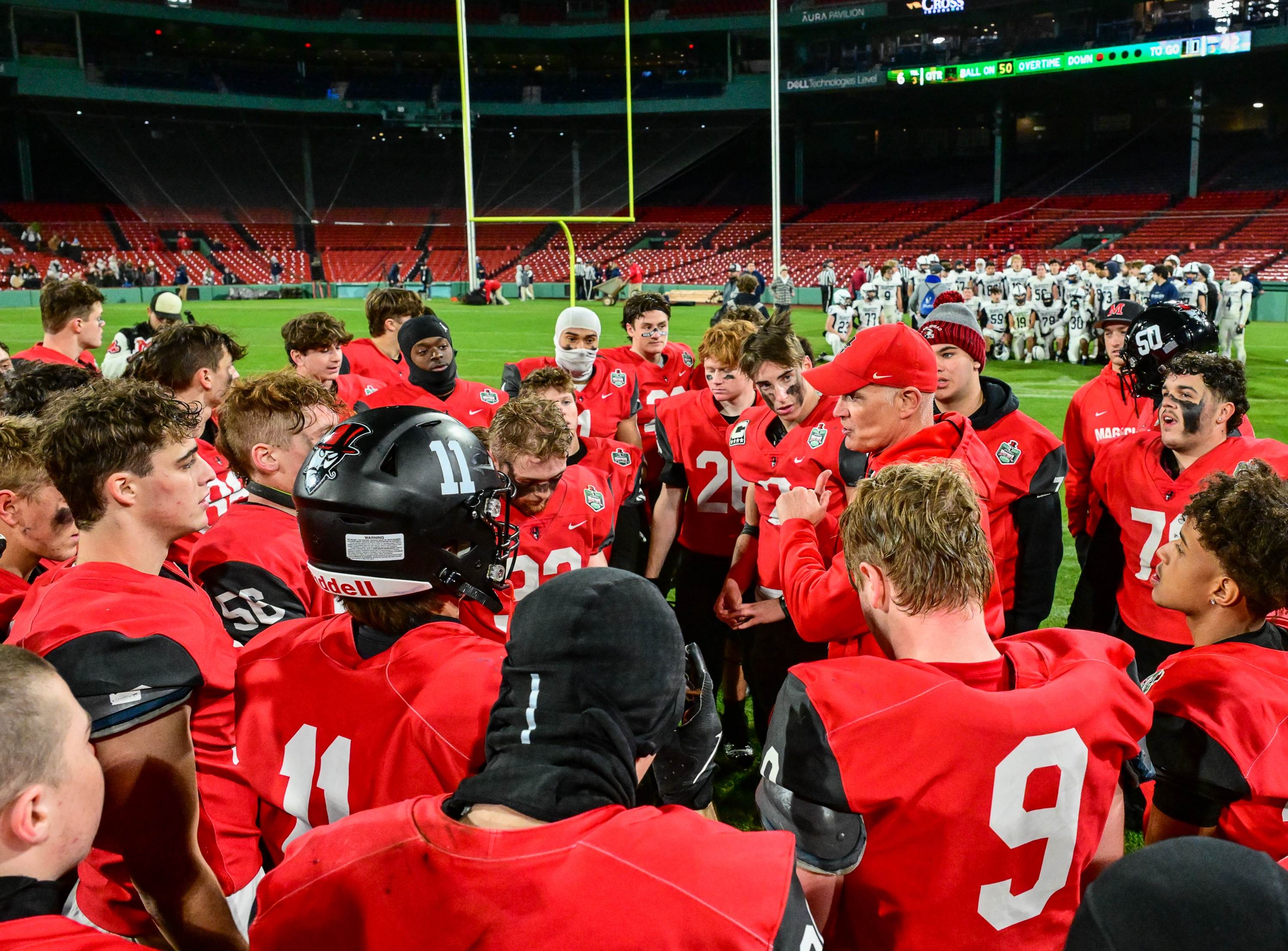 Marblehead huddles up at Fenway Park after its win over Swampscott, who is taking a team photo in the back. (Photo: Mike Braca)