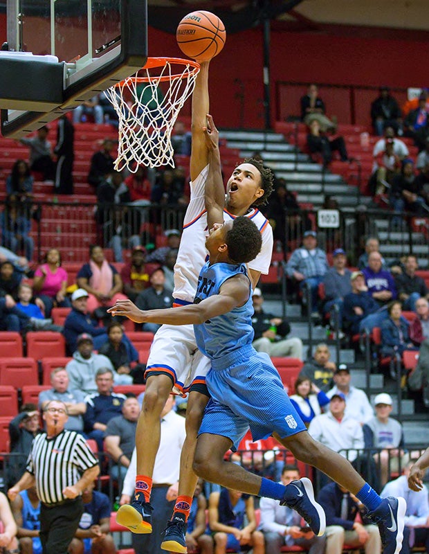 East St. Louis's (III.) Joe Reece soars over Belleville East's Jared Adams for a dunk during the SWC event at SIUE's Vadalabene Center.
