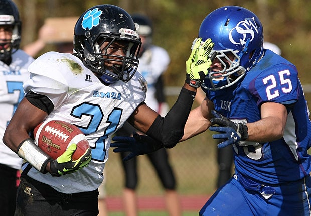 A running back for Sports & Medical Sciences Academy/University Science & Engineering (Hartford, Conn.) fends off an Old Saybrook-Westbrook (Saybrook, Conn.) tackler.