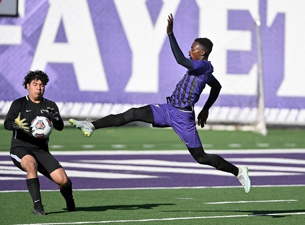 Bentonville West keeper Alejandro Aldaco fends off a shot by Fayetteville’s Shea Glover during a match on April 14. 