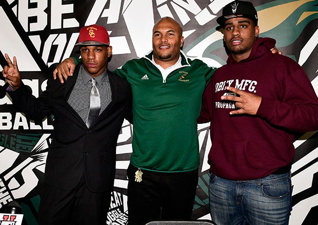 Antonio Pierce poses for pictures with 2015 Long Beach Poly signees Iman Marshall (left) and Joseph Wicker. (Photo: David Hood)