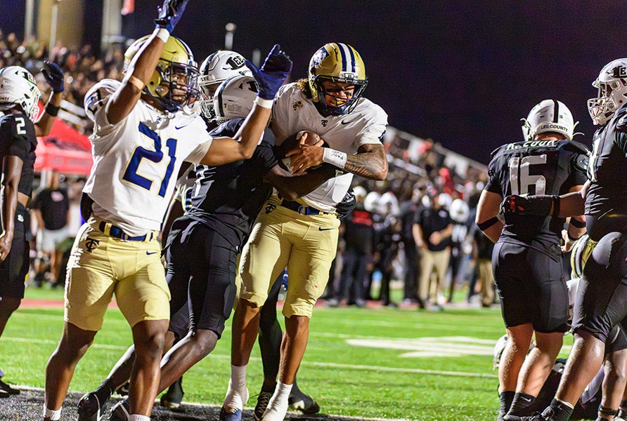 Aidan McPherson and teammates celebrate a touchdown during their win Friday at Trojan Field, which was packed in anticipation of a showdown between nationally-ranked programs. (PHOTO: Greg Giedd)