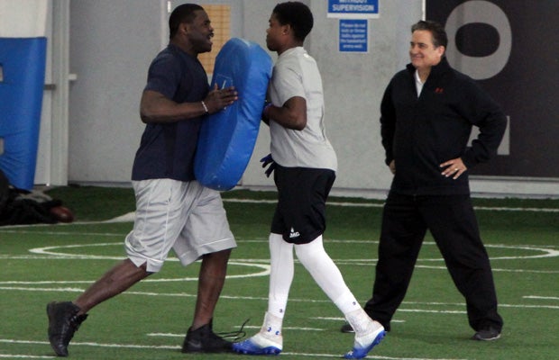 Former head coach Steve Mariucci can’t help but grin as Osborn is on the receiving end of a hand shiver from NFL Hall of Famer Michael Irvin.
