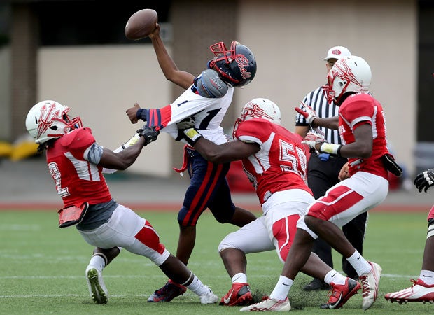 Erasmus Hall (N.Y.) quarterback Aaron Grant is pressured by a swarm of Flushing defenders.