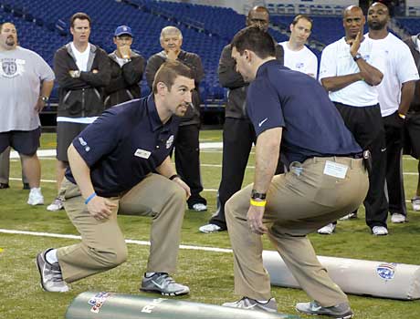 Andy Ryland and Gabe Infante demonstrate a tackling drill while former NFL players look on.