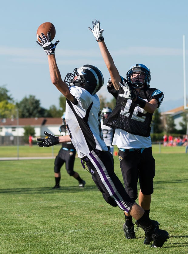A Riverton (Utah) High player leaps for a catch against West Jordan (Utah) player.
