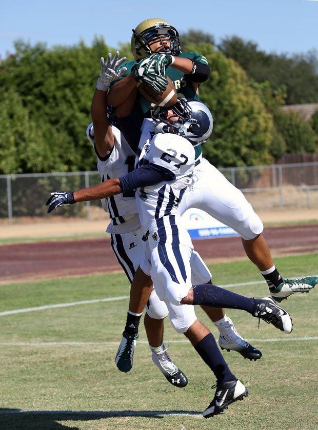 Kadyn Silva of Rio Americano (Sacramento, Calif.) leaps over two defenders from Casa Roble (Orangevale, Calif.) in an attempt to make a grab.