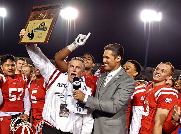 Mater Dei coach Bruce Rollinson holds up hardware after the Monarchs won their first Southern Section crown since 1999.