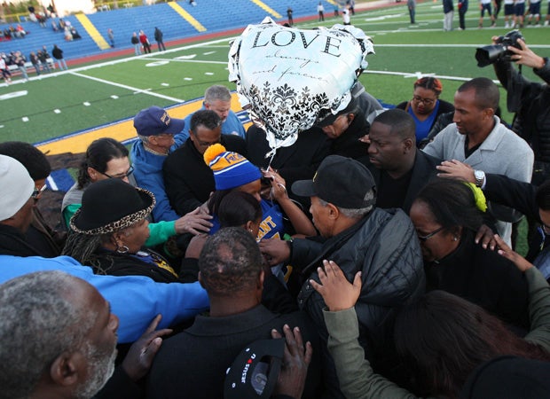 Nicole Clavo (middle) is swarmed by well-wishers as they pray at midfield before the start of the game.