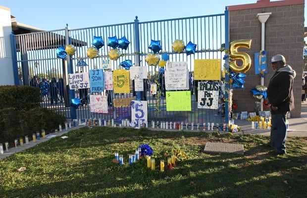 A man looks at a memorial set up for Jaulon Clavo outside the home entrance to the Grant football stadium.