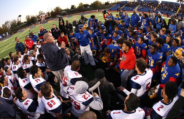 Players and coaches from Grant and Beyer high schools gather at midfield to pray in honor of slain football player Jaulon Clavo before the start of their playoff game Monday night.