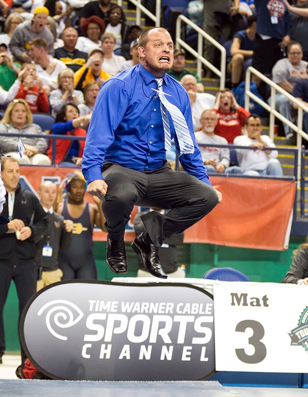 A Hickory Ridge (N.C.) coach leaps while celebrating a victory by his wrestler in the finals of the NCHSAA 3A state championships.