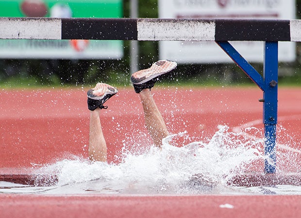 A John Jay (Hopewell Junction, N.Y.) steeplechase runner enters the water hazard awkwardly after tripping on the barrier during the Kingston Tiger Relays in New York.