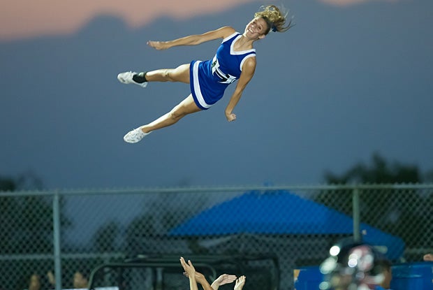 A Hebron (Carrollton, Texas) cheerleader goes high into the mountain sky in a game against Mansfield Timberview.