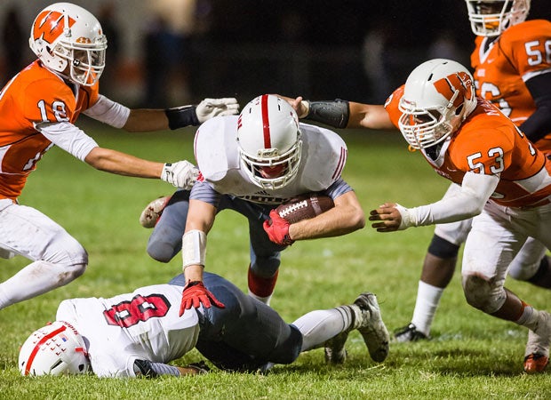 A Winters (Calif.) player leaps over one of his own players while trying to avoid two Woodland defenders.