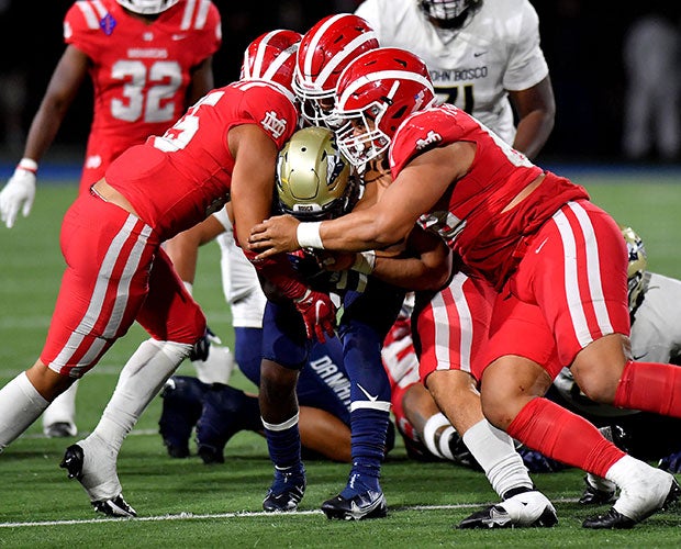 Three Mater Dei defenders stuff a Bosco ballcarrier.