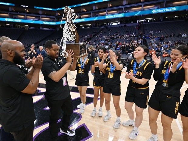 Whitney coach Myron Jacobs hold up the California girls Division IV trophy after the Wildcats beat Half Moon Bay 48-40 on Saturday at Golden 1 Center in Sacramento. Whitney jumped out to a 10-point lead to start the game and led wire-to-wire. (PHOTO: David Steutel)