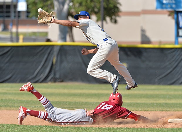 A Brawley (Calif.) infielder leaps in an attempt to catch a pickoff throw from the catcher while a McClatchy (Sacramento, Calif.) baserunner dives safely back to second base during a game in the 67th Annual San Diego Lions Tournament.
