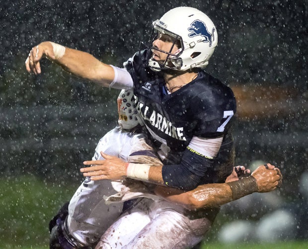 Bellarmine Prep (Wash.) quarterback Christian Moore is hit by Sumner linebacker Ben Wilson after releasing a pass in a driving rain storm.