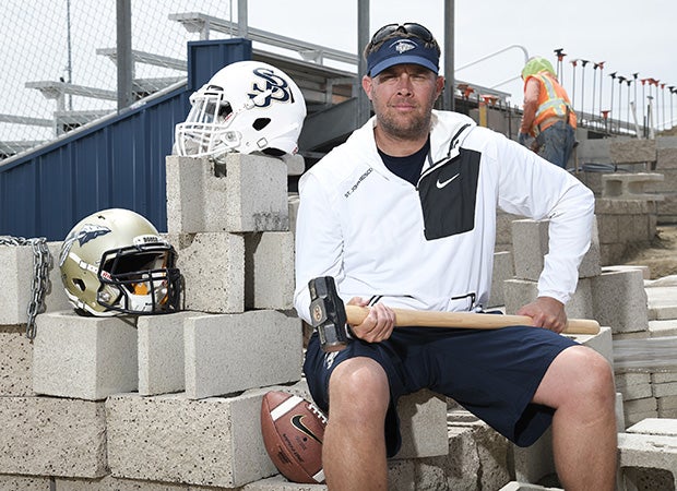 Head coach Jason  Negro sits in front of the school's new stadium under construction.