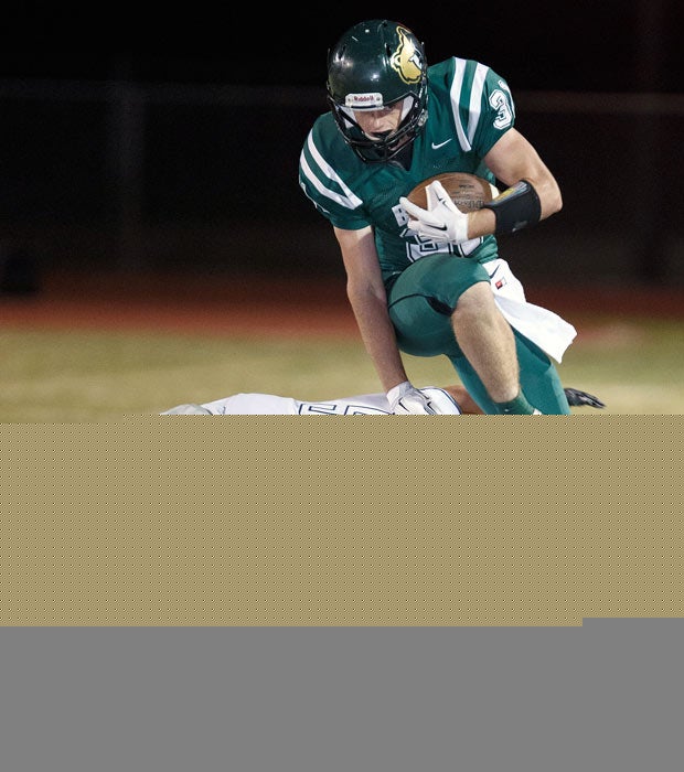 Basha (Ariz.) running back Zach Reed attempts to leap over a Perry defender.