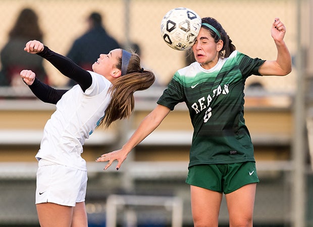 A Johnson (San Antonio) player hits a header behind a Reagan (San Antonio) player during a game in Texas.  