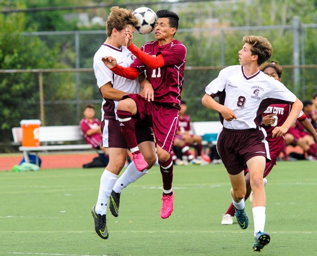 A Garden City player (left) and a Glen Cove player trap the ball while battling for a header during a soccer game in New York.