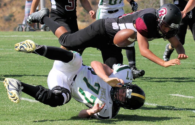 A Sierra Ridge/Rite of Passage (Calif.) player (top) fumbles the ball while colliding with an Incline defender.