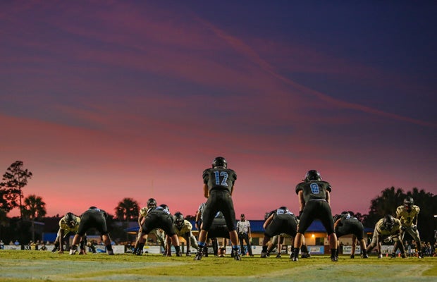 A spectacular sunset lights up the sky as Ponte Vedra (Fla.) quarterback Nick Tronti awaits the snap during a game against Oakleaf in Florida.