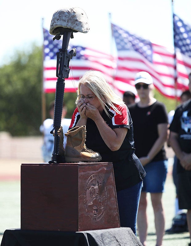 Patty, a Gold Star mother, clutches military dog tags during ceremonies before one of the Honor Bowl games on Sept. 11 at Liberty High School in Northern California.   