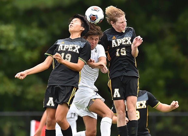 Apex (N.C.) players Danny Hwang (left) and Campbell Baldwin compete with Ben Poirier of Broughton for the header in August.