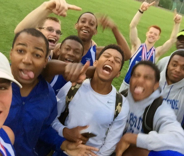 Imoter Mngerem (tongue out) is mobbed by teammates during track and field practice at Riverside Military Academy.