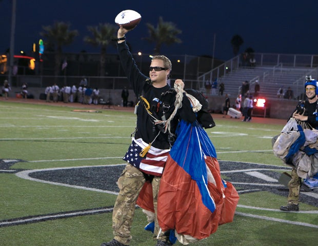 A parachuter delivers the game ball before Centennial faced Serra in the Honor Bowl on Saturday night at Oceanside High School. 