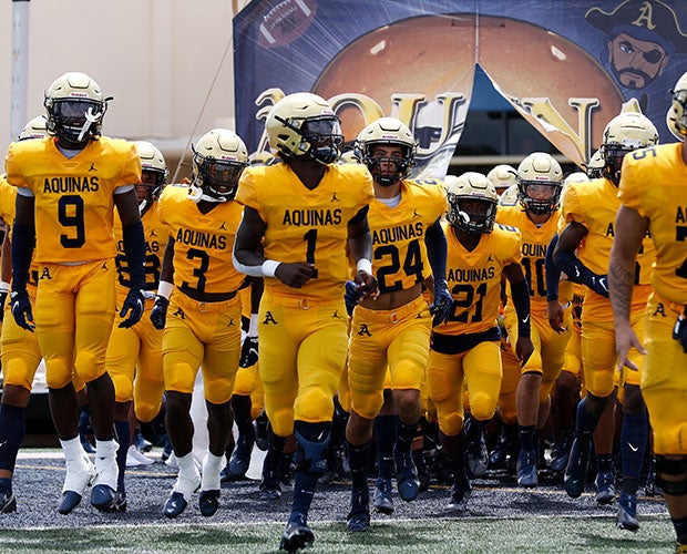 No. 6 St. Thomas Aquinas players run onto the home field for their season opener.