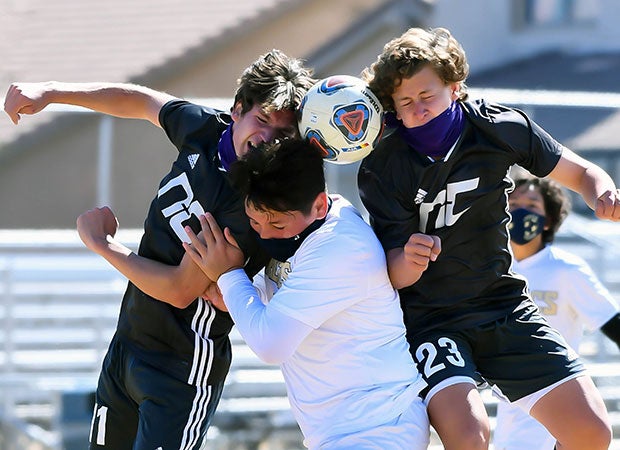 Two Northwest Christian (Ariz.) players battle a Parker player (middle) for a header.