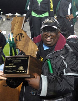 Long Beach Poly coach Don Norford holding up
one of his 14 state girls championships, this
one from 2011. 